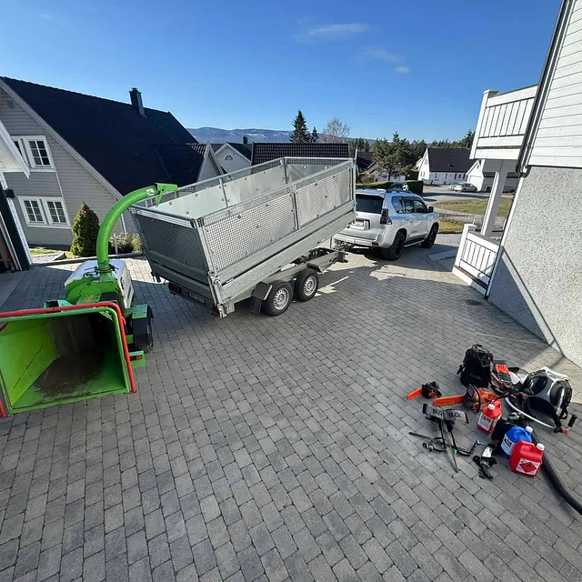 Flishugger og tilhenger parkert i oppkjørsel med verktøy og utstyr klart til trefelling.
