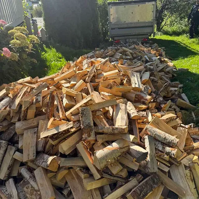 Stor haug med oppkappet ved liggende på bakken klar for transport eller lagring.